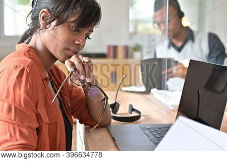 Office worker woman in open space area, protected by plexiglas