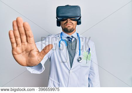 Young arab doctor man with concentated expression wearing uniform and using 3d glasses over isolated white background.