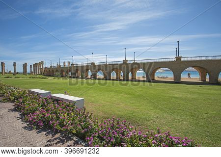 View Across A Beautiful Landscaped Garden In Tropical Resort With Large Bridge And Archways On Beach