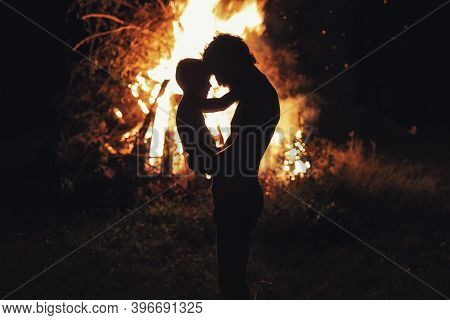 Father Holding His Little Son With Burning Bonfire On Background, Fatherhood And Joy Of Life. Light 