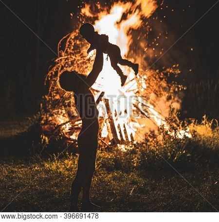 Father Holding His Little Son With Burning Bonfire On Background, Fatherhood And Joy Of Life. Light 