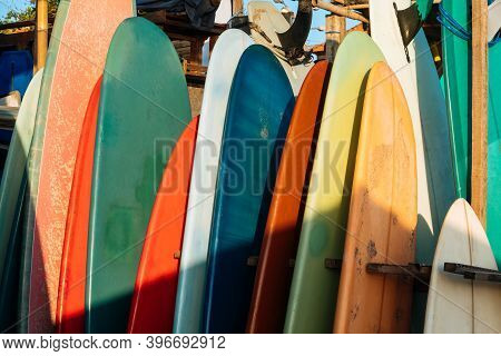 Set Of Different Color Surf Boards In A Stack By Ocean.bali.indonesia. Surf Boards On Sandy Beach Fo