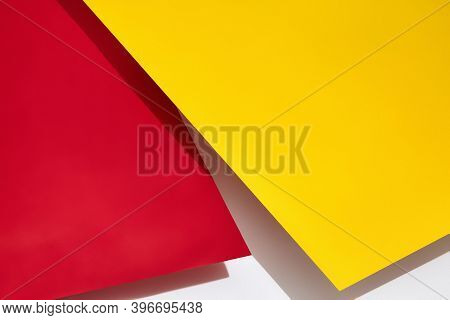 Red And Yellow Shadow-casting Sheets Of Paper Or Stands Above White Surface. Advertising, Branding A