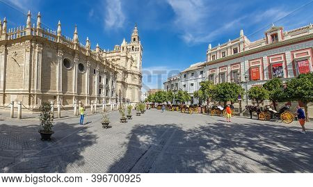 Seville, Spain - October 18. 2020: Horse Drawn Carriages At Plaza Triunfo With Tourists At The Back 