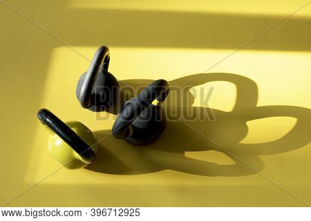 Three Kettlebells Staying On A Yellow Floor In The Gym. Kettlebells With Shadows. Sunny Day In Gym