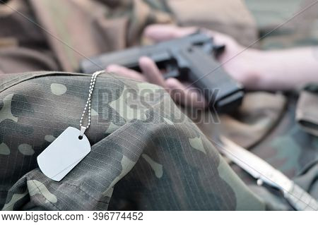 Army Token Lies On Camouflage Uniform Of Dead Soldier And Hand With Pistol