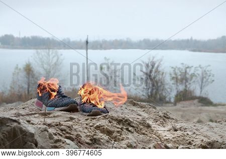 Burning Sports Sneakers Or Gym Shoes On Fire Stand On Sandy Beach Coast. Athlete Burned Out. Physica