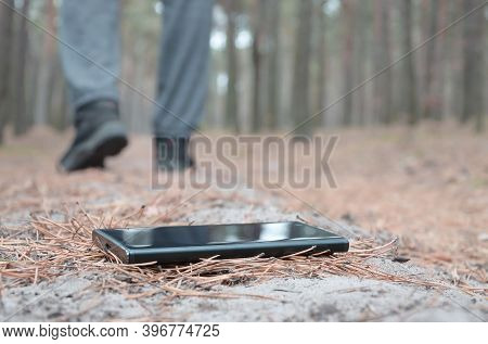 Young Man Loses His Smartphone On Russian Autumn Fir Wood Path. Carelessness And Losing Expensive Mo