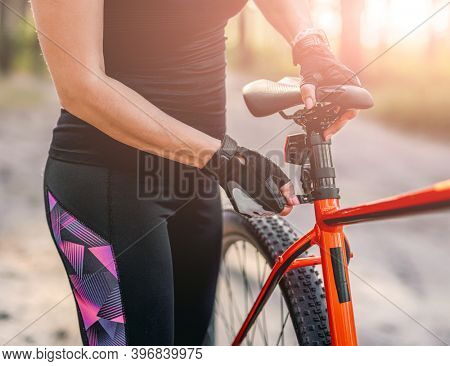 Girl rising bike seat in nature