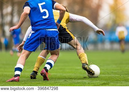 Adult Soccer Players Compete In A Tournament Match. Footballers In A Duel. Boys Kicking Soccer Ball 