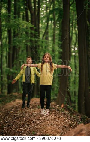 Little Boy And Girl With Raised Arms Enjoying The Fresh Air In Beautiful Forest.