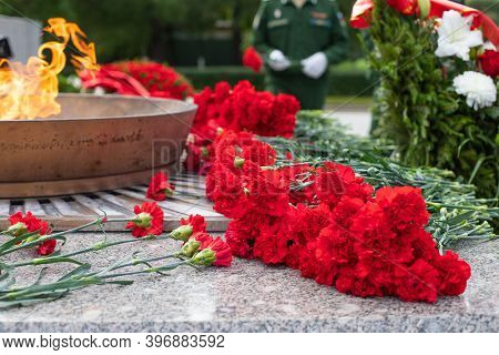Laying A Red Carnation In Memory Of The Dead. Red Carnations On A Granite Gravestone.memorial Comple