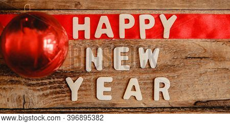 Happy New Year Inscription In Wooden Letters On A Wooden Table. The Word Happy On The Red Ribbon. Ne
