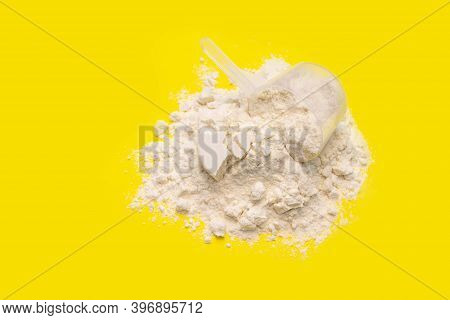 Pile Of Banana Collagen Powder And Measuring Cup Isolated On Yellow Background