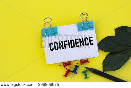 Confidence - Word On A White Sheet With Clips On A Yellow Background With Buttons, A Green Sheet And