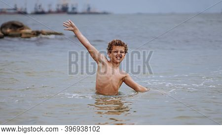 Curly-haired Boy With A Happy Face Of A Sports Physique Bathes In The Sea