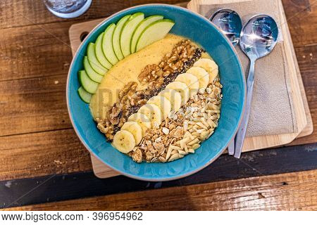 Healthy Smoothie Bowl Breakfast With Granola, Cut Banana, Sliced Apples, And Various Types Of Nuts