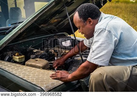 Serengeti, Tanzania - July 3 2008: Black Man Repairing A Landrover Safari Jeep In Africa. An African