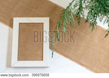 Desktop Mock Up With White Wooden Picture Frame On The Textured Burlap Cloth. Zero Waste, Eco Friend