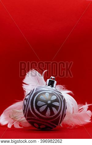 Christmas Ball And Feathers Over Red Background