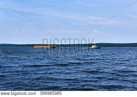 Transportation Of Timber Along The River Using A Barge Towed By A Tug