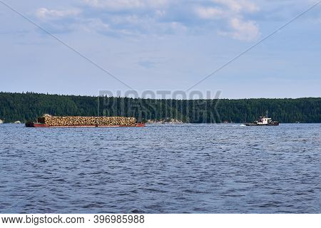 Transportation Of Timber Along The River Using A Barge Towed By A Tug