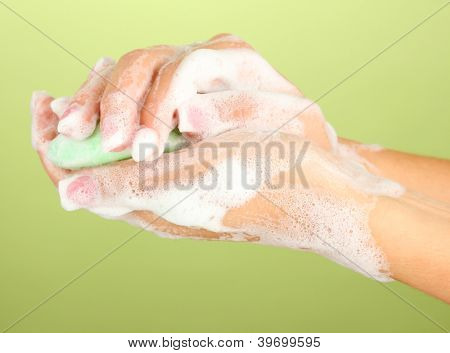 ผู้หญิงมือใน soapsuds บนพื้นหลังสีเขียวอย่างใกล้ชิด