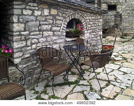 Chairs and table on stone patio in Greece