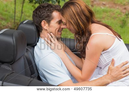Young couple feeling romantic in back seat of convertible in countryside