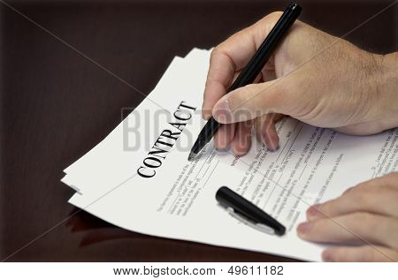 Business man signing contract with bladk pen on desk