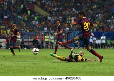 KUALA LUMPUR - AUGUST 10: Barcelona's Cristian Tello (20) kicks past Malaysia's Mahalli Jasuli (fallen) in a game at the Shah Alam Stadium on August 10, 2013 in Malaysia. Barcelona wins 3-1.