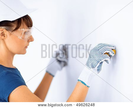 architecture and home renovation concept - female architect measuring wall with flexible ruller