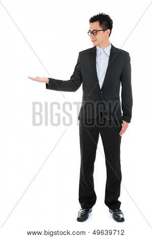 Full body portrait of young handsome smiling Asian business man hand showing blank empty space, standing isolated over white background