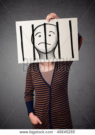 Woman holding a paper with a prisoner in jail behind the bars on it in front of her head