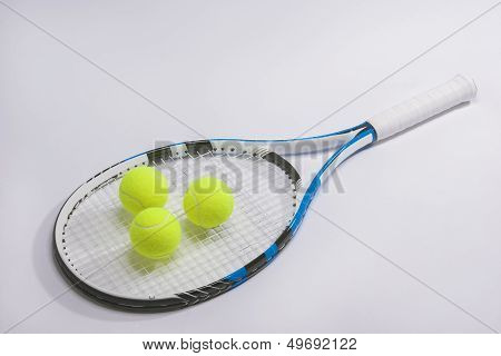Closeup Of A Full Legth Tennis Racket And Three Balls On White Background