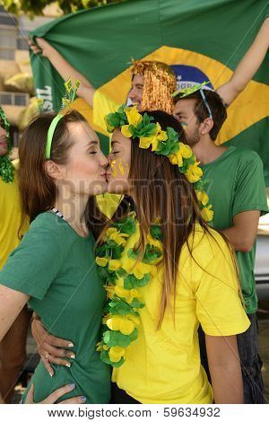 Cheerful couple of Brazilian girlfriends soccer fans kissing each other celebrating.