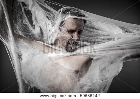 Danger. man tangled in huge white spider web