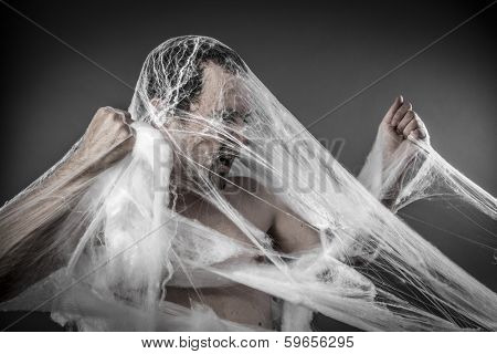 Danger. man tangled in huge white spider web