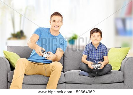 Young man playing video game with his younger cousin, at home