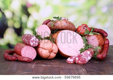 Lot of different sausages on wooden table on natural background