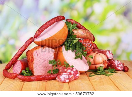 Lot of different sausages on wooden table on natural background