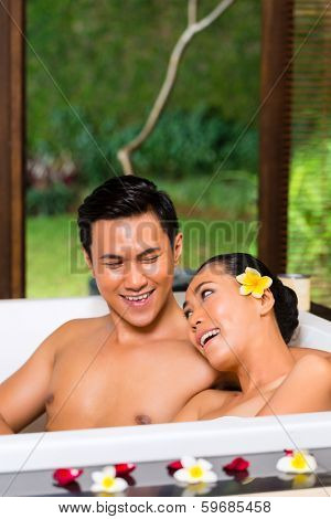 Indonesian Asian couple in wellness beauty day spa having aroma therapy bath with essential oils or salt, looking relaxed