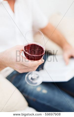 leisure, drinks, education and lifestyle concept - close up of male hand holdind book and glass of red wine