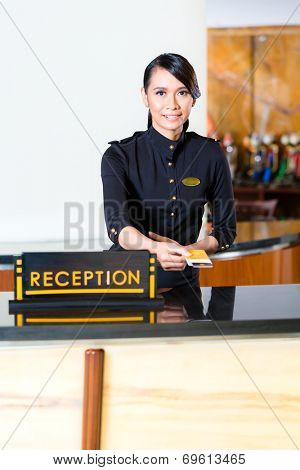Portrait of receptionist passing keycard in hotel