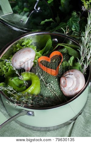 raw vegetables in a saucepan and heart carrots, vegan