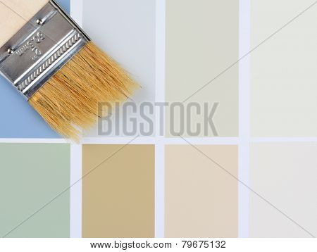Closeup overhead shot of a paint brush laying on a color sample chart. Vertical format with the brush in the upper left corner, with copy space.