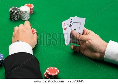 casino, gambling, poker, people and entertainment concept - close up of poker player with playing cards and chips at green casino table