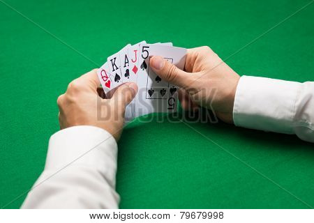 casino, gambling, poker, people and entertainment concept - close up of poker player holding playing cards at green casino table