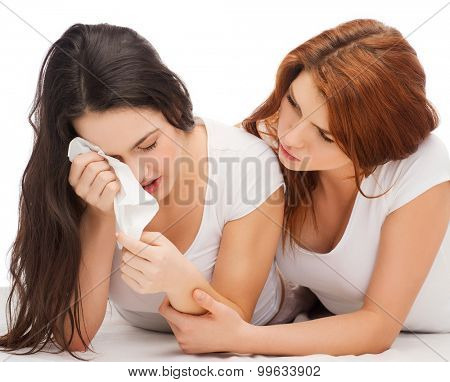 friendship and happy people concept - one teenage girl comforting another after break up