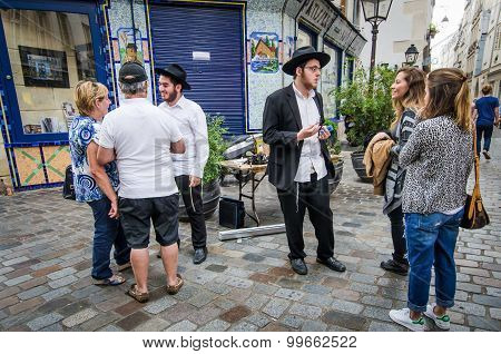 Street scene in Marais with Orthodox Jewish young men talking with tourists